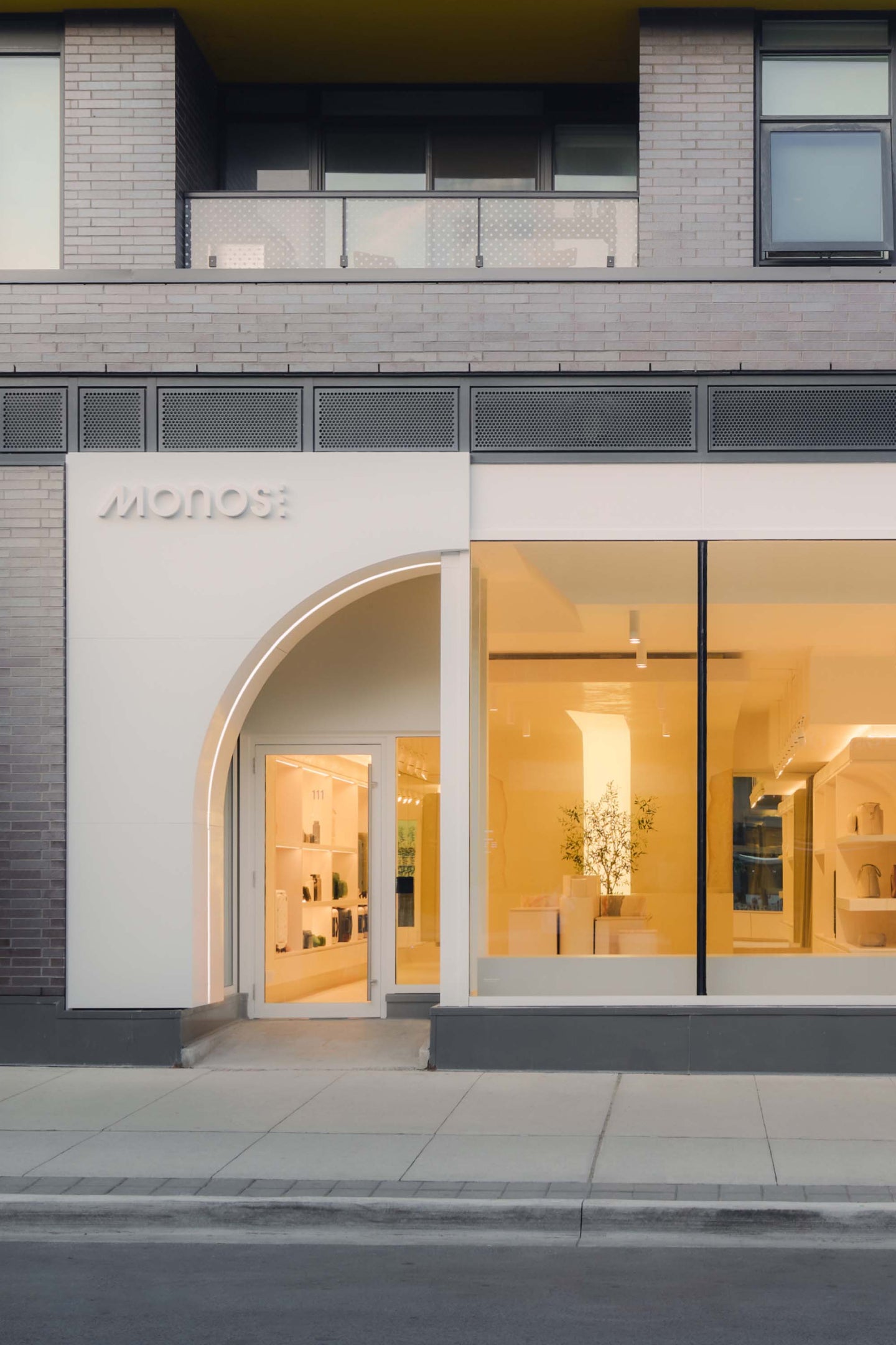 The exterior of the Monos Ossington retail store, featuring large windows that showcase a bright and modern interior with minimalist displays.