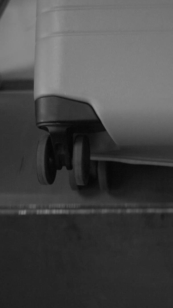 Close-up of the base of a Monos Carry-On with wheels being tested on a conveyor-like system, demonstrating the durability of its wheels.