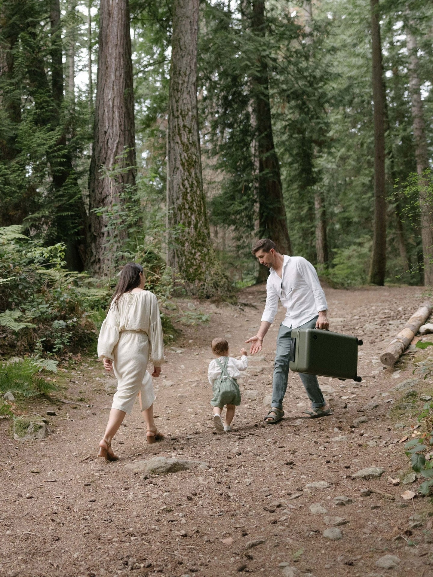 A family walking in the forest holding a Carry-On in Olive Green