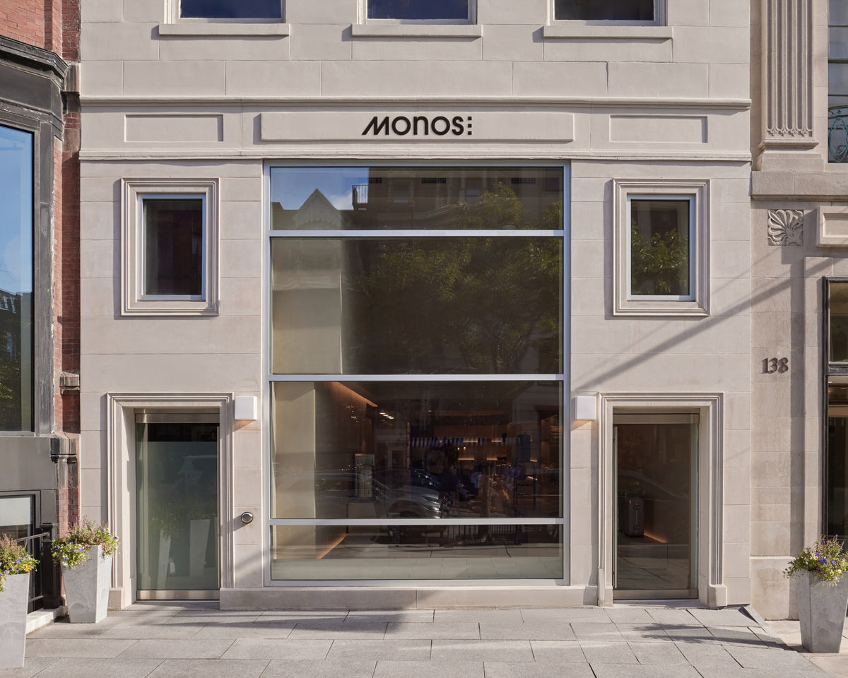 Monos Boston store exterior on Newbury Street with large glass windows and minimal stone façade in daylight.